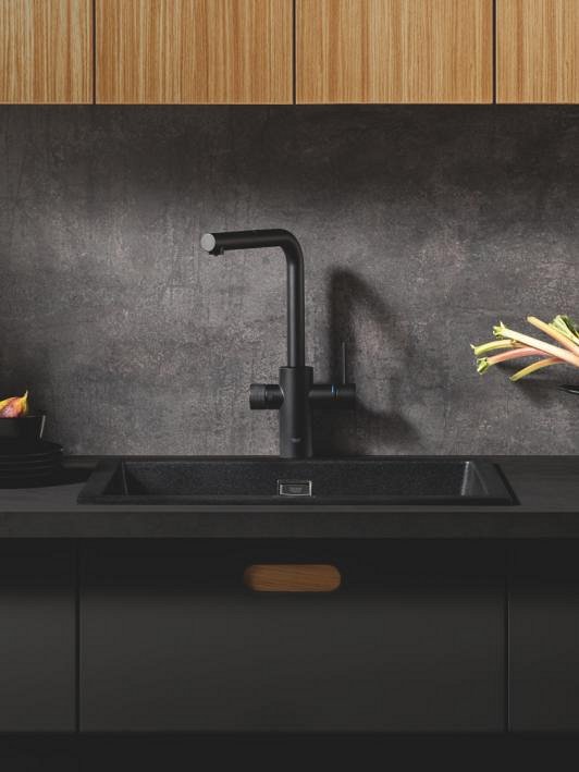 Змішувач для кухні GROHE у кольорі Фантомний чорний на сірому тлі з дерев'яними шафами зверху.