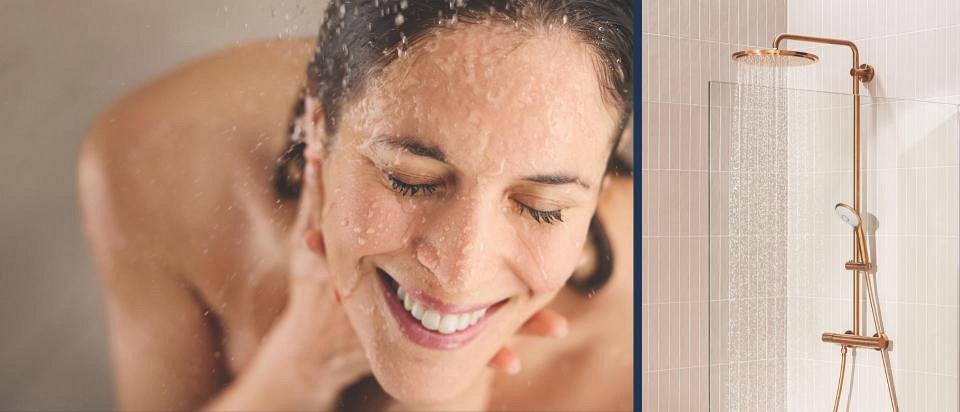 Uśmiechnięta kobieta podczas prysznica i system prysznicowy GROHE w kolorze złotym Warm Sunset. Uśmiechnięta kobieta podczas prysznica i system prysznicowy GROHE w kolorze złotym Warm Sunset.