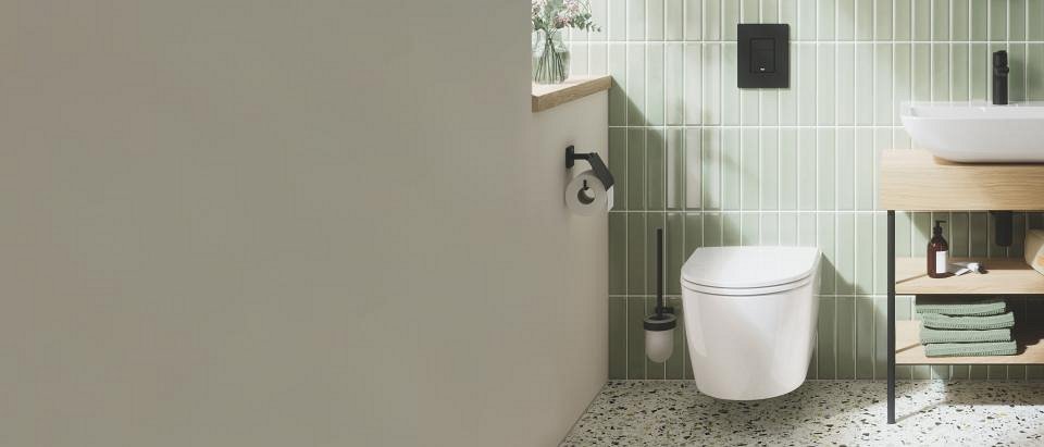 Een modern badkamer ontwerp met een strak hangtoilet en een zwarte bedieningsplaat tegen een achtergrond van lichtgroene verticale tegels.