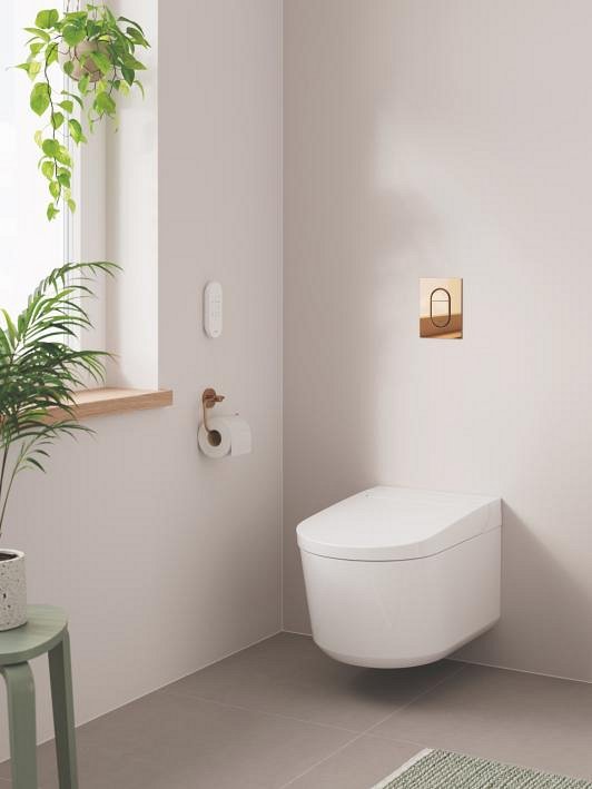Sprchová toaleta GROHE Sensia v béžové koupelně se zlatým splachovacím tlačítkem 