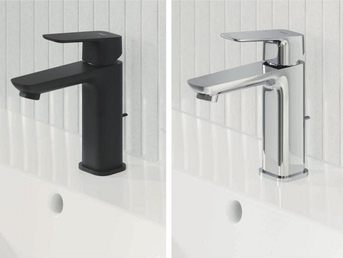 Două baterii de baie GROHE Cubeo unul lângă celălalt, unul în negru mat și celălalt în crom, montate pe chiuvete albe cu backsplash-uri de gresie