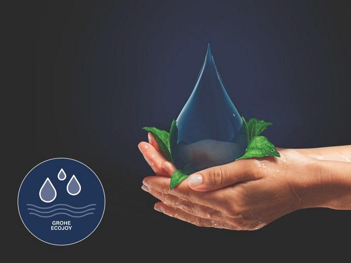 Mâini care țin o picătură mare de apă înconjurată de frunze verzi, cu logo-ul GROHE EcoJoy în colț