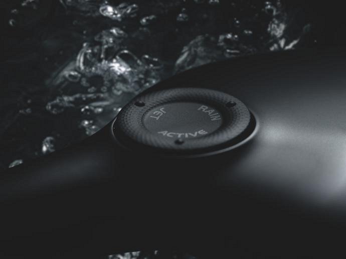 The dial on the back of a GROHE hand shower in Phantom Black, water in the background.