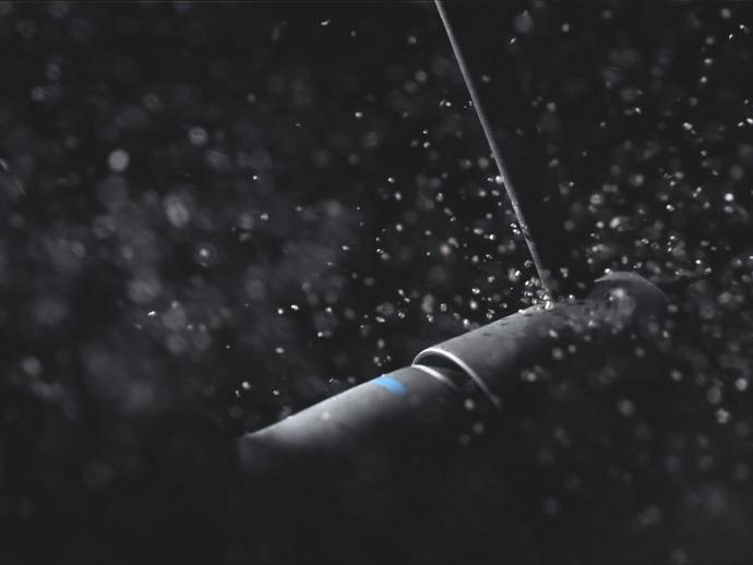A GROHE tap in Phantom Black, covered in water droplets.