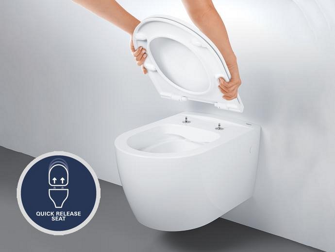 A hand lifting the toilet seat off a modern white toilet, demonstrating the Quick Release feature, which allows easy removal of the toilet seat.