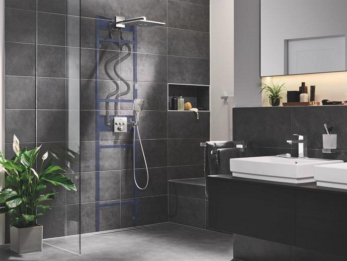 A contemporary bathroom featuring dark grey tiles, with a GROHE Rapido Shower Frame used to install the concealed shower system.