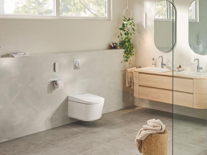 A GROHE Sensia PRO shower toilet in a beige and grey-decorated bathroom with wooden cabinets.