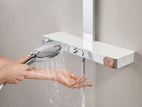 Close-up of a person's hand testing the temperature of water coming out of a hand shower, the side bar can be seen in the background.