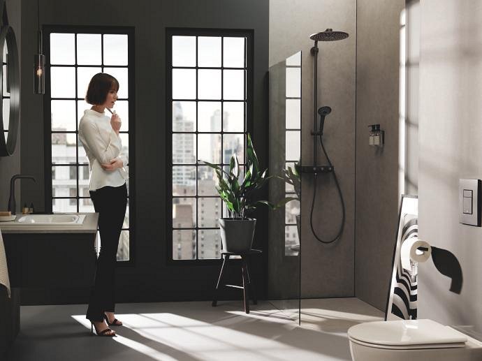 Una persona de pie en el cuarto de baño, mirando la ducha que contiene un mezclador GROHE Phantom Black.