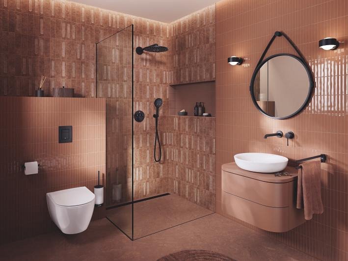 Modernes Bad mit GROHE Produkten, mit begehbarer Dusche, wandmontiertem WC und stilvollem Waschbecken in einem eleganten erdigen Farbton.