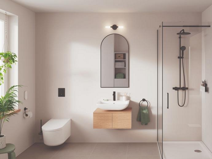 Un WC con funzione bidet GROHE Sensia in un bagno beige con rubinetto, sistema doccia e accessori nero opaco.