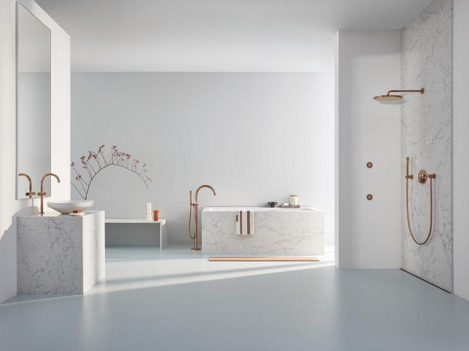 Stijlvol ontworpen badkamer met gouden en bronzen GROHE-kranen, beige muren en zacht natuurlijk daglicht.