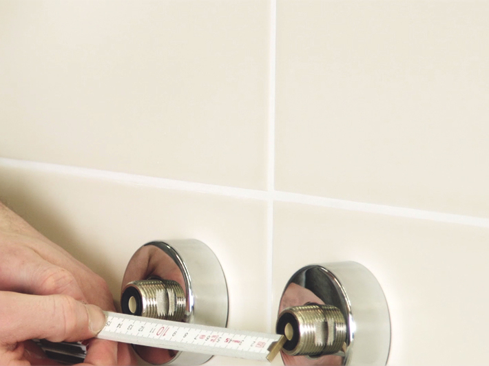 Measuring the center-to-center spacing between shower supply connections and chrome escutcheons on tile