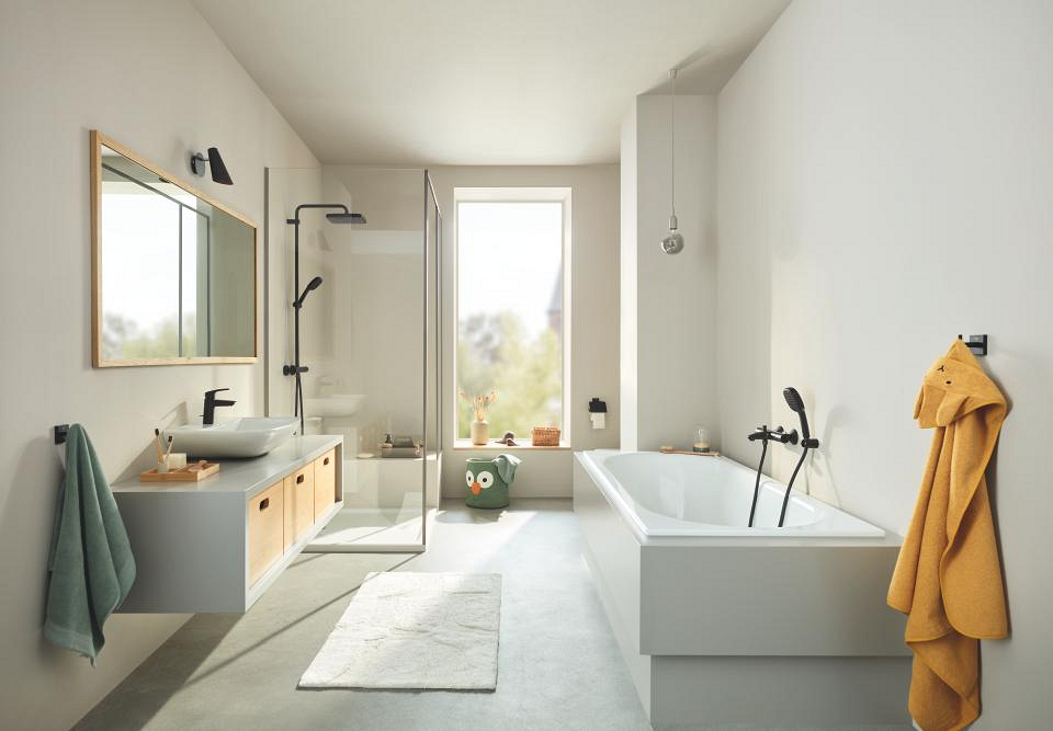 Een badkamer met mat zwarte wastafelkraan, badkraan, douche en accessoires 